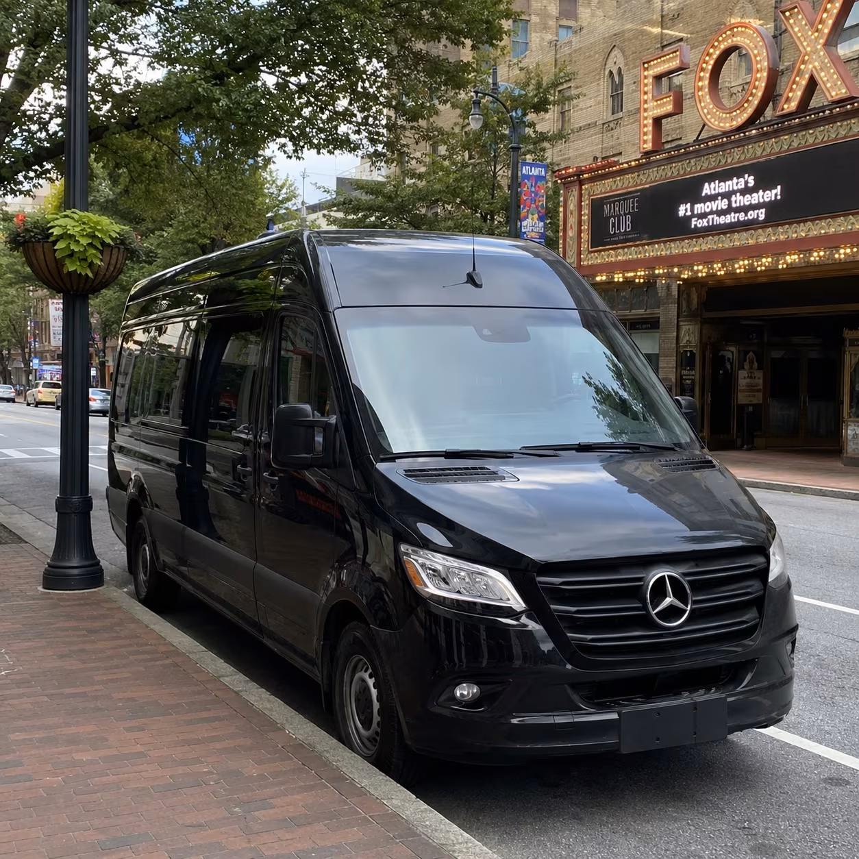 Black Mercedes Sprinter van and charter bus parked outside a Atlanta venue